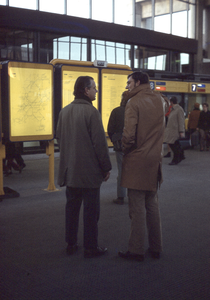 801785 Afbeelding van enkele personen bij de vertrektijdenborden in de nieuwe Stationshal van het Centraal Station ...